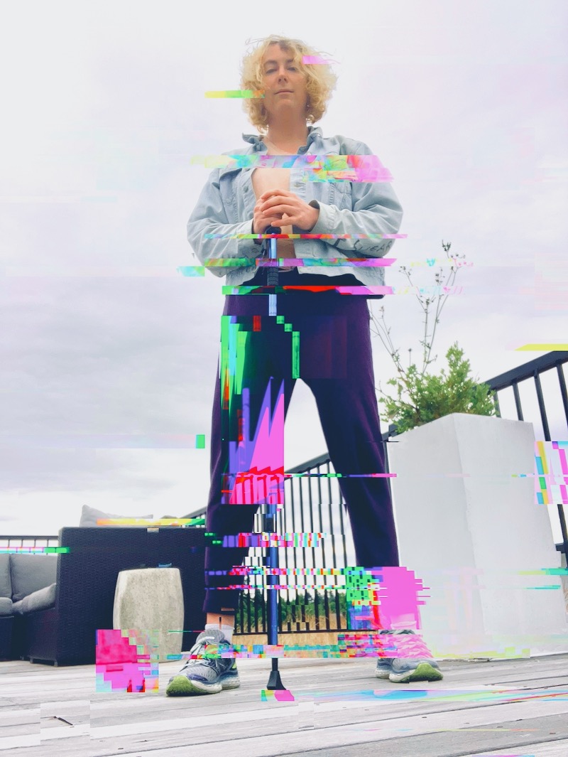 Lyra McMahon, a white transfeminine disabled person standing with one walking stick